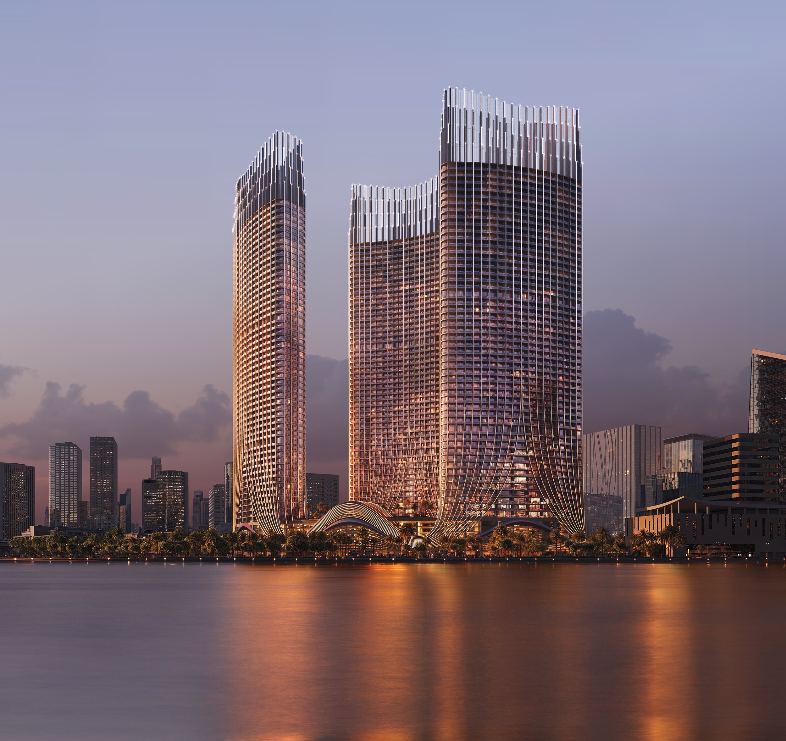 Binghatti Skyrise skyscrapers with reflective glass facade at sunset, water body in front